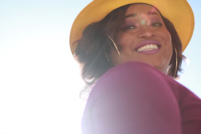 A joyful woman wearing Luna Brill earrings and necklace, smiling in natural light.
