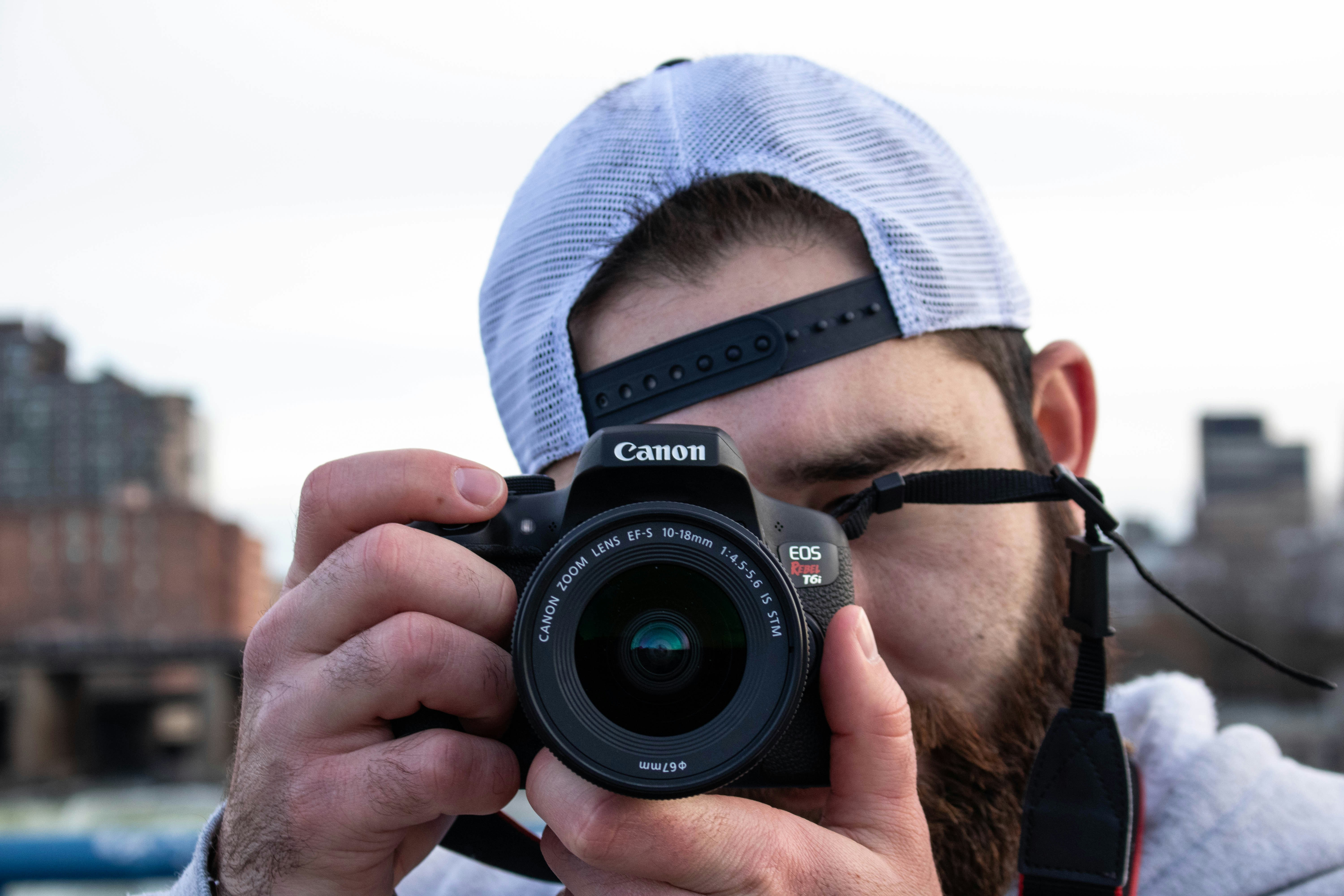 man in blue knit cap holding black nikon dslr camera