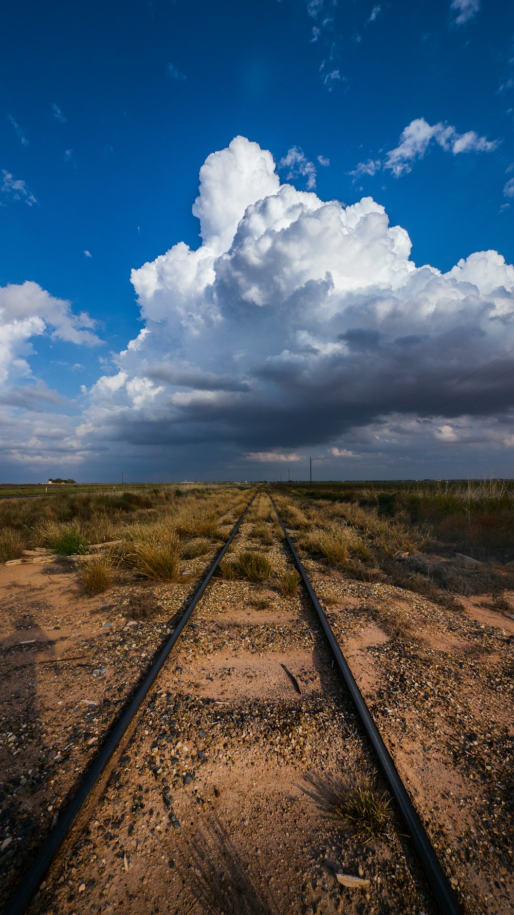 train rail under blue sky and white clouds during daytime