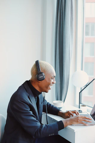 A friendly customer support agent wearing a headset, smiling while assisting a client on a laptop.