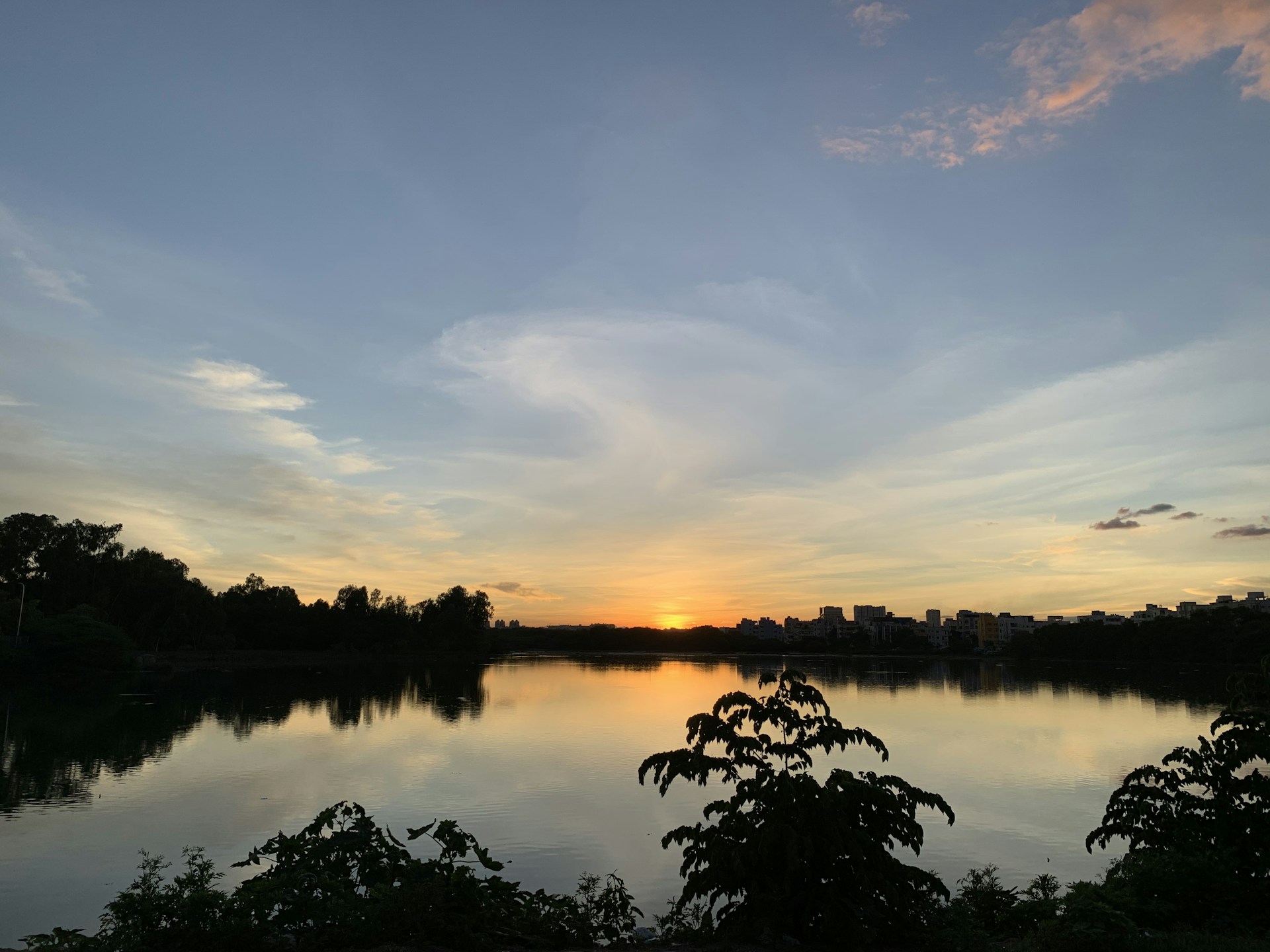 A serene landscape shot of a calm lake at sunset, reflecting the colorful sky and surrounding nature.