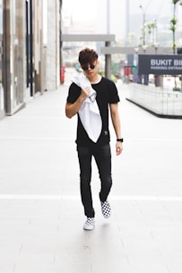 A young man confidently walking down a city street wearing classic cargo pants paired with a casual white tee.