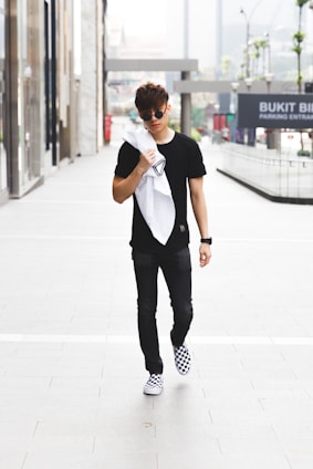 Young man walking confidently through a vibrant city street wearing stylish urban clothing from el abem.
