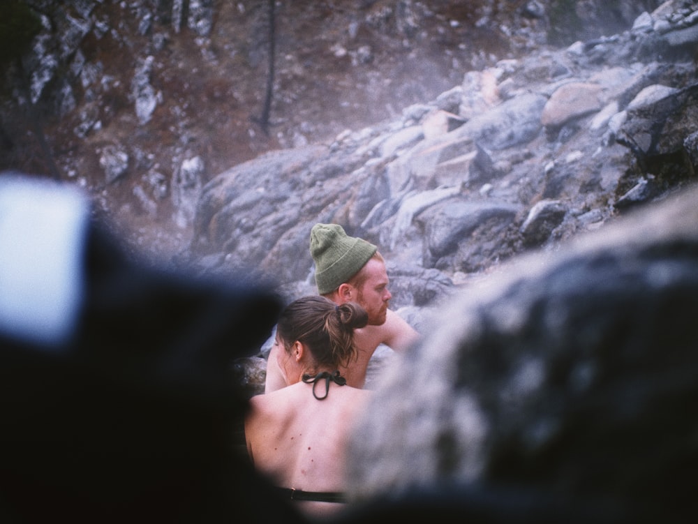 Donna in canotta nera e berretto a maglia grigio in piedi sulla montagna rocciosa durante il giorno