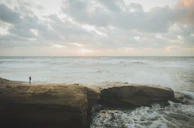 A silhouette of a lone figure standing on a cliff under a stormy sky.