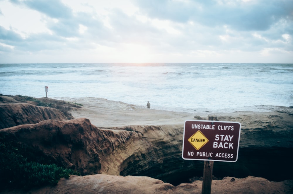 person standing on brown rock near sea during daytime