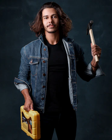 Handyman holding a toolbox standing confidently in front of a cozy home.