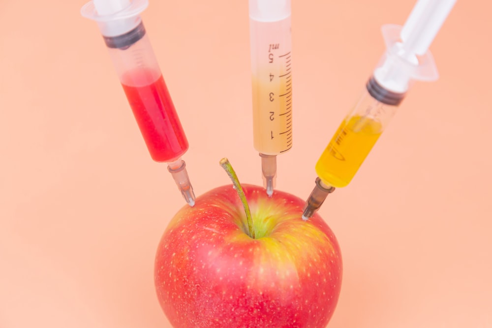 pomme rouge à côté d’une bouteille en verre transparent