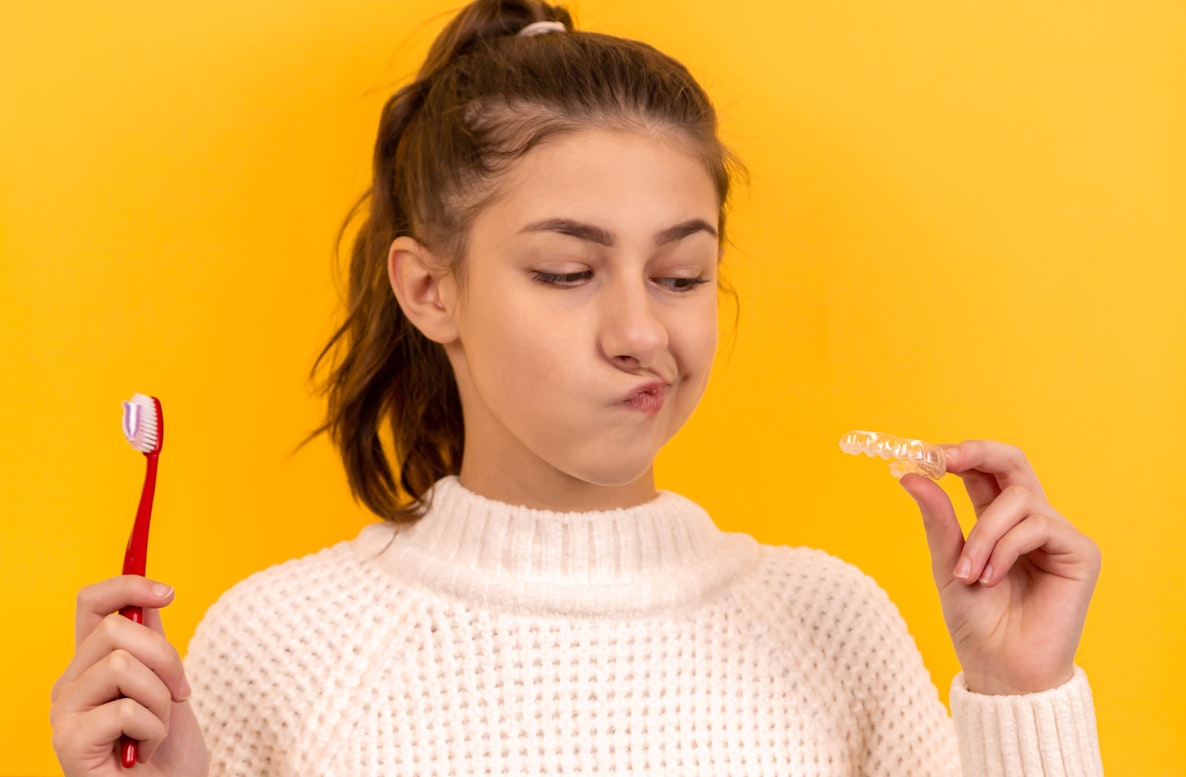 a girl in a white sweater holding a toothbrush.