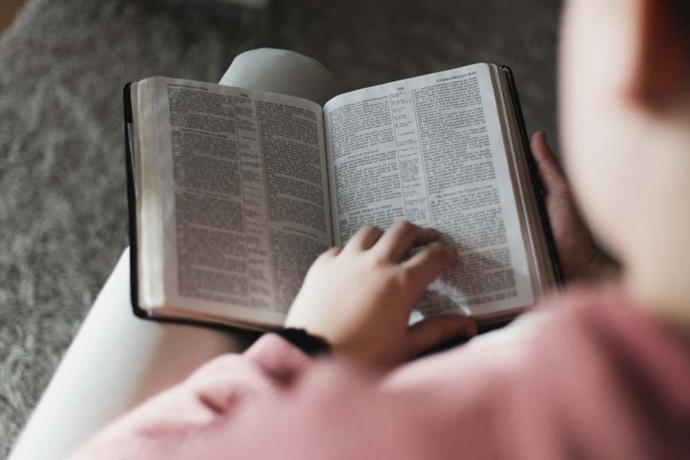 person reading book on brown wooden table