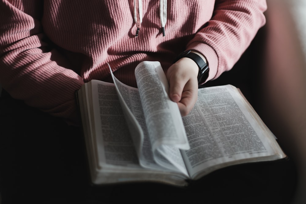 personne en chemise à manches longues rayée rouge et blanche tenant un livre