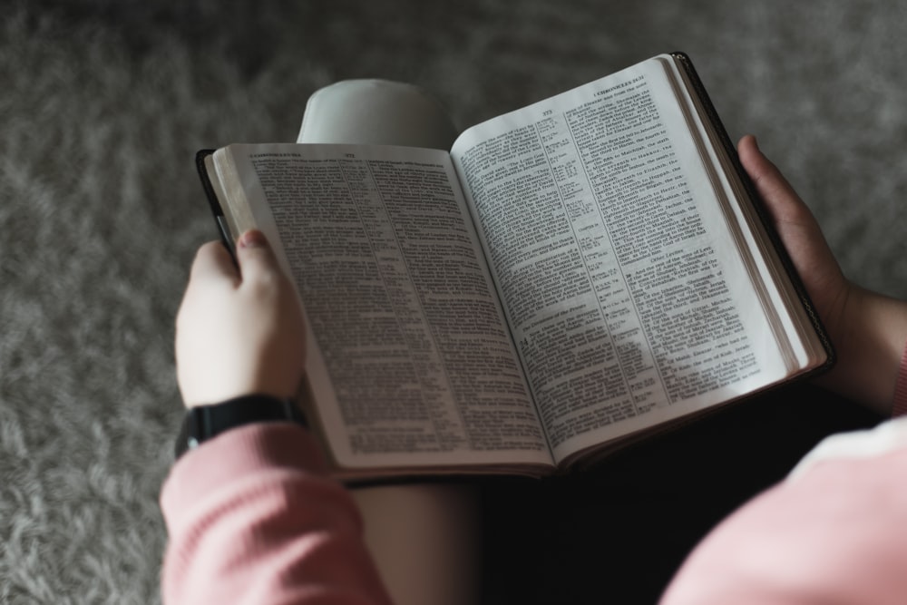 person in pink long sleeve shirt reading book