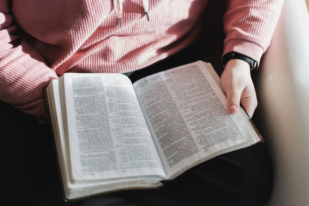 person in pink and white striped long sleeve shirt reading book