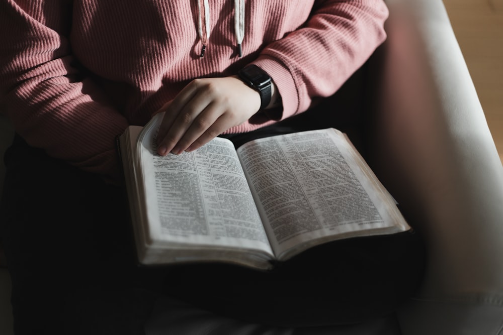 person in pink long sleeve shirt reading book