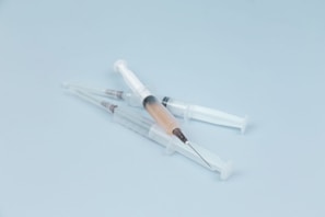 A close-up of elegant dermal filler syringes arranged on a marble surface.