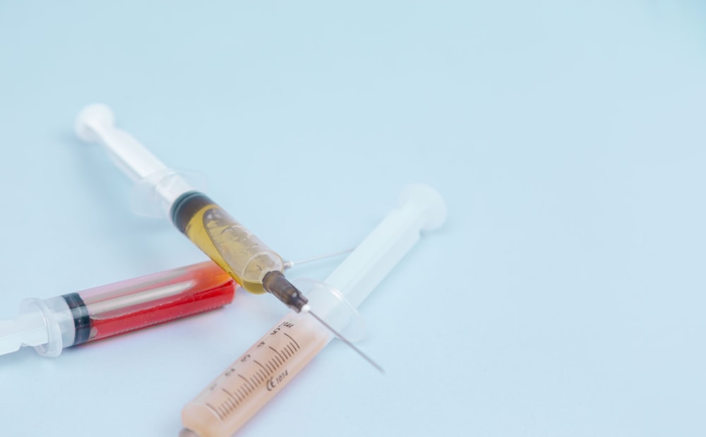 white and orange syringe on white surface