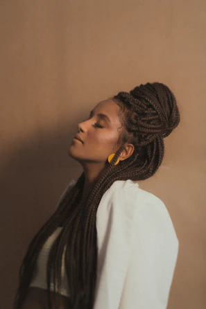 Close-up of elegant long braids styled on a black woman with a soft cream background