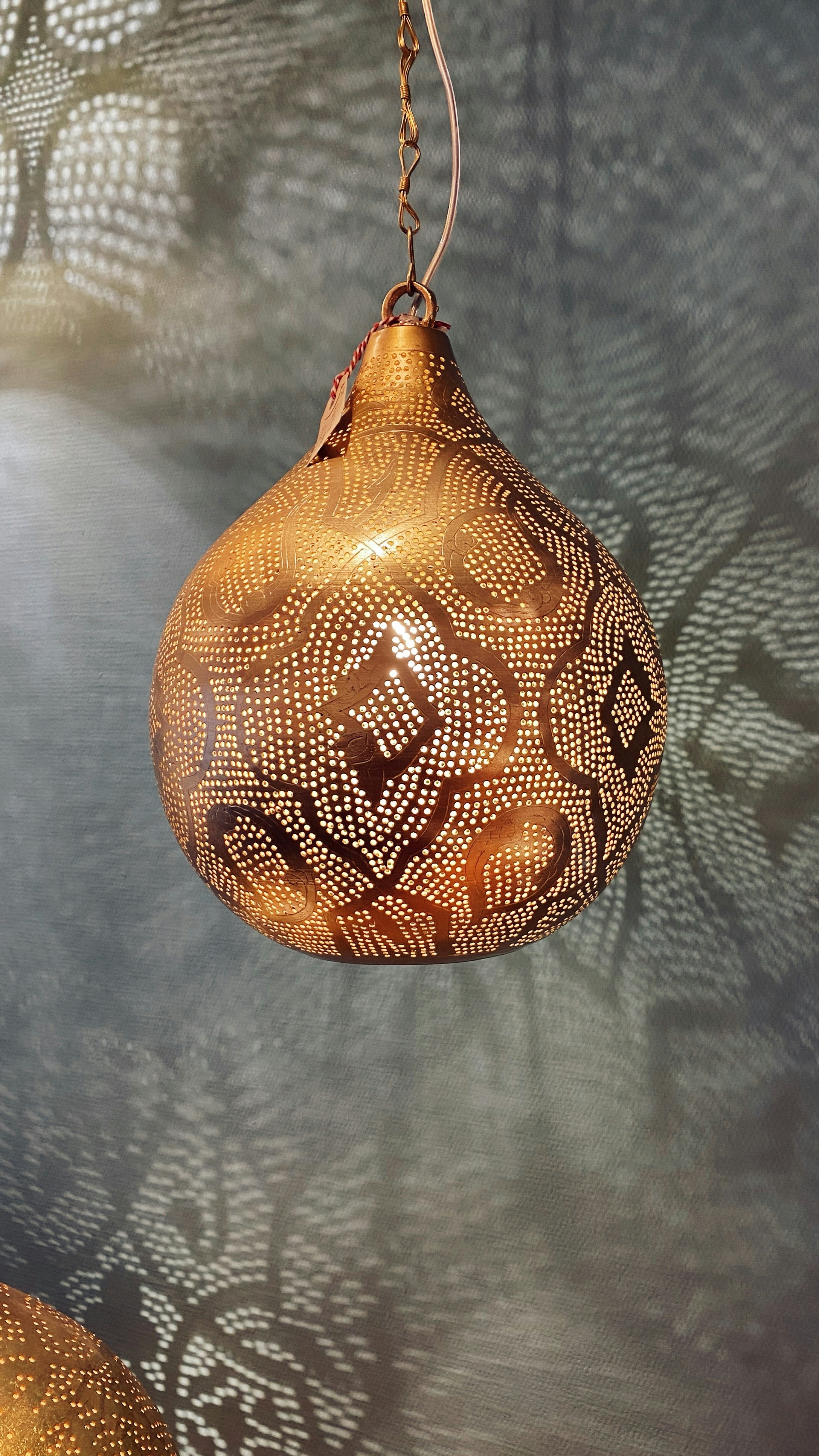 a golden light hanging from a chain on a wall