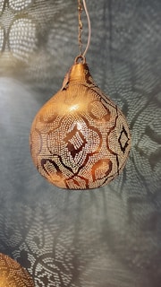 a golden light hanging from a chain on a wall