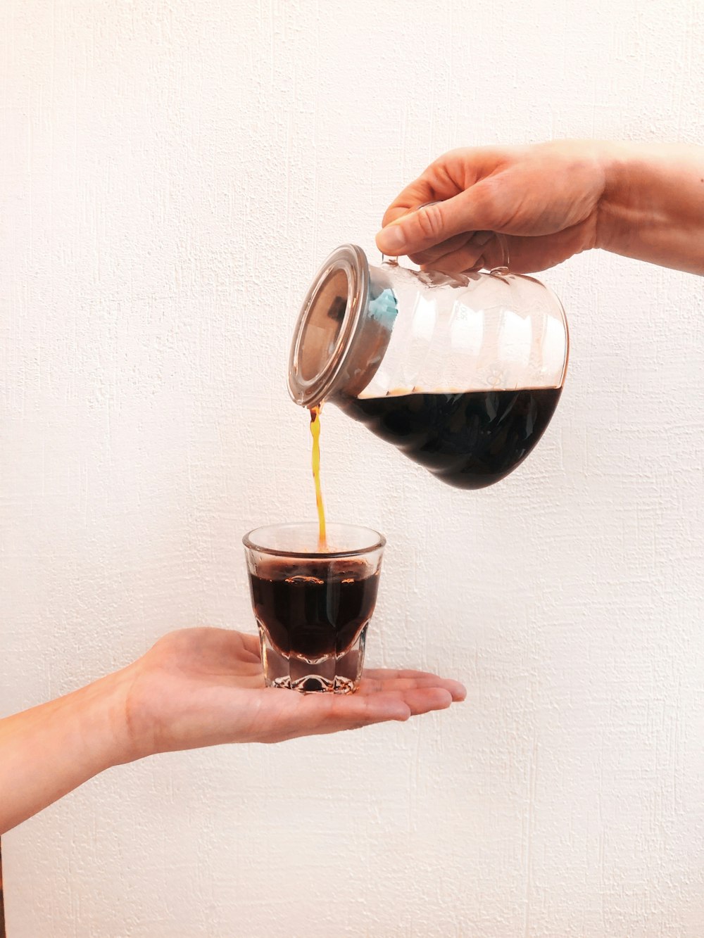 person holding clear glass cup with black liquid