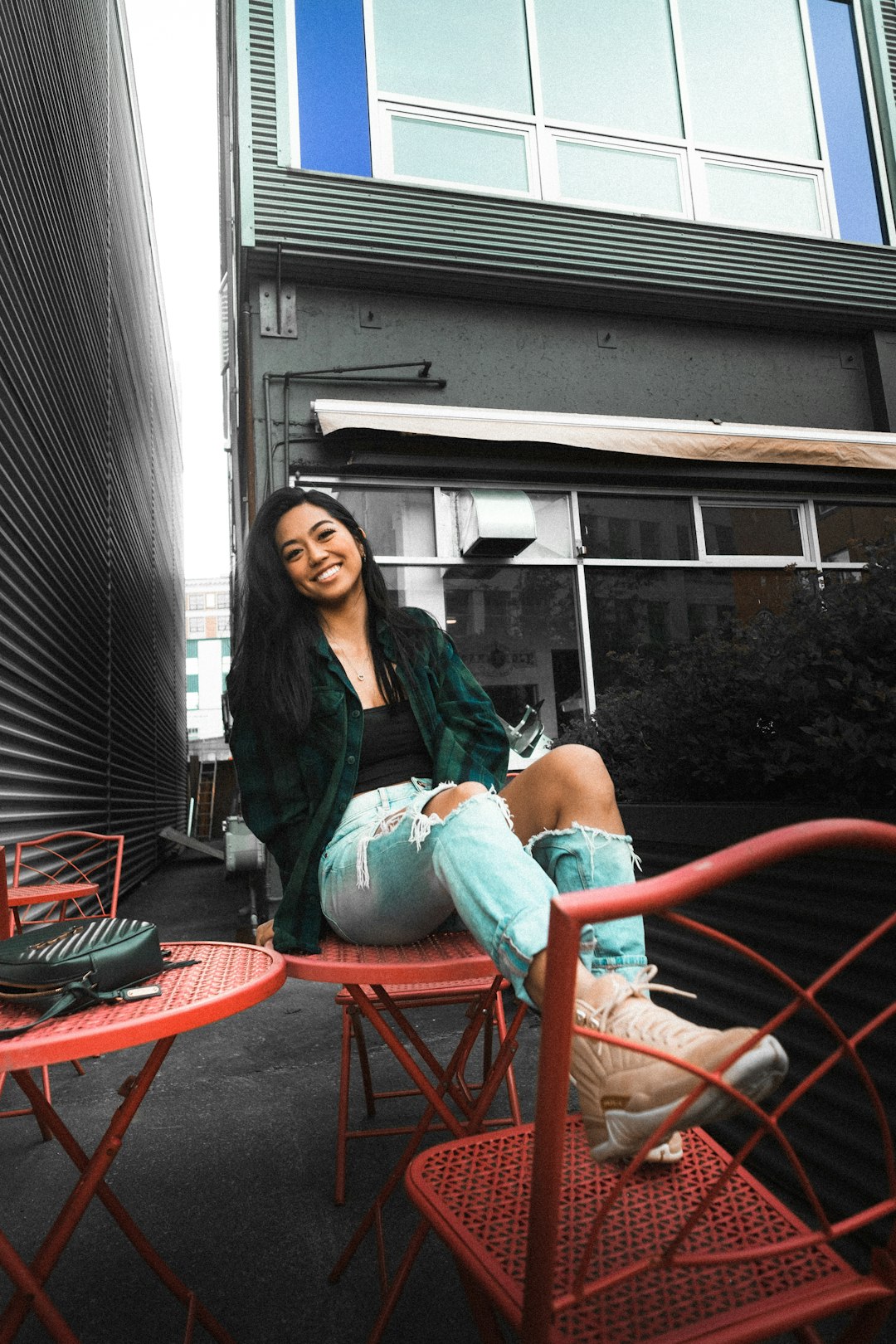 woman in black cardigan sitting on red metal chair