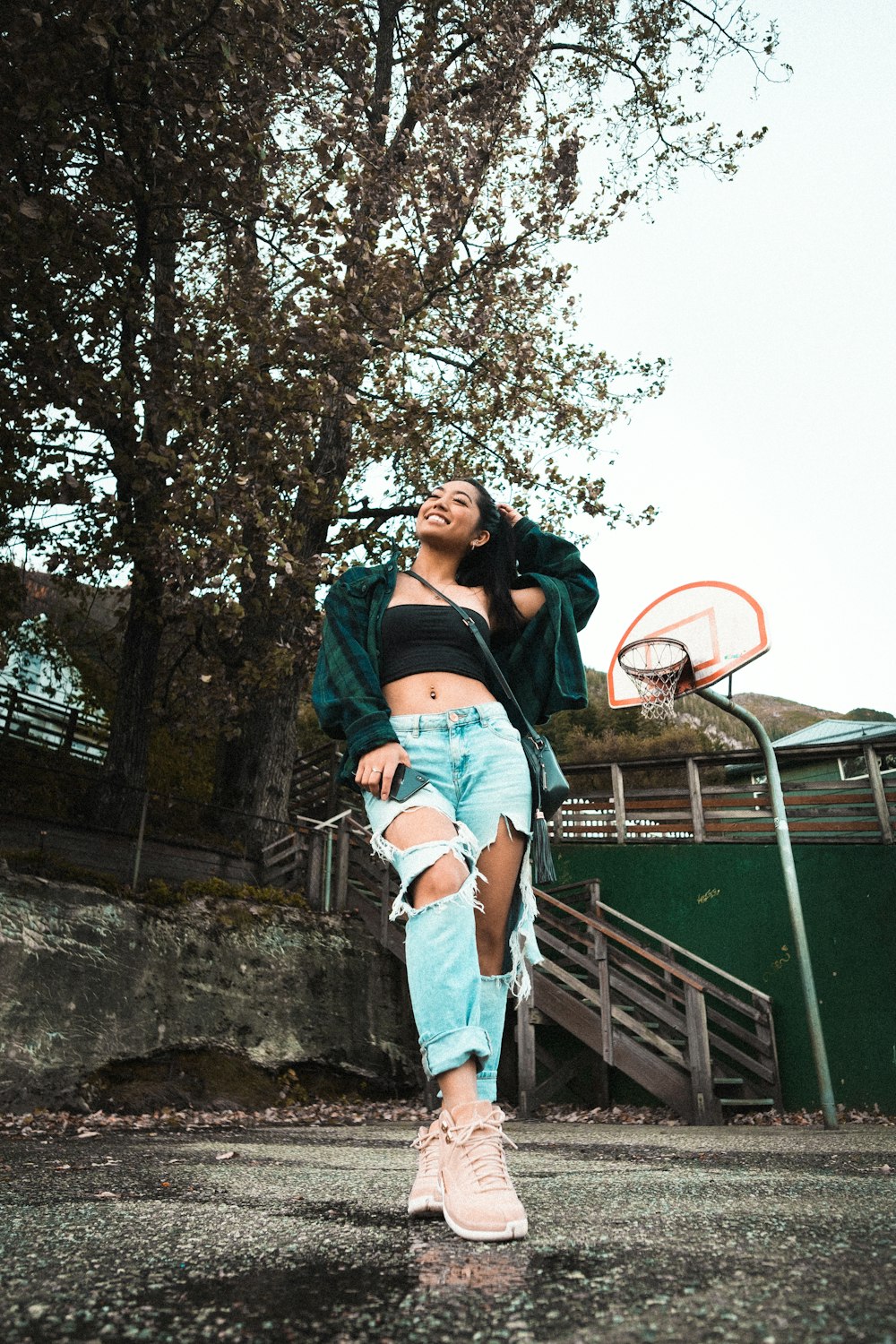 woman in black crop top and blue denim shorts standing beside green and brown trailer during