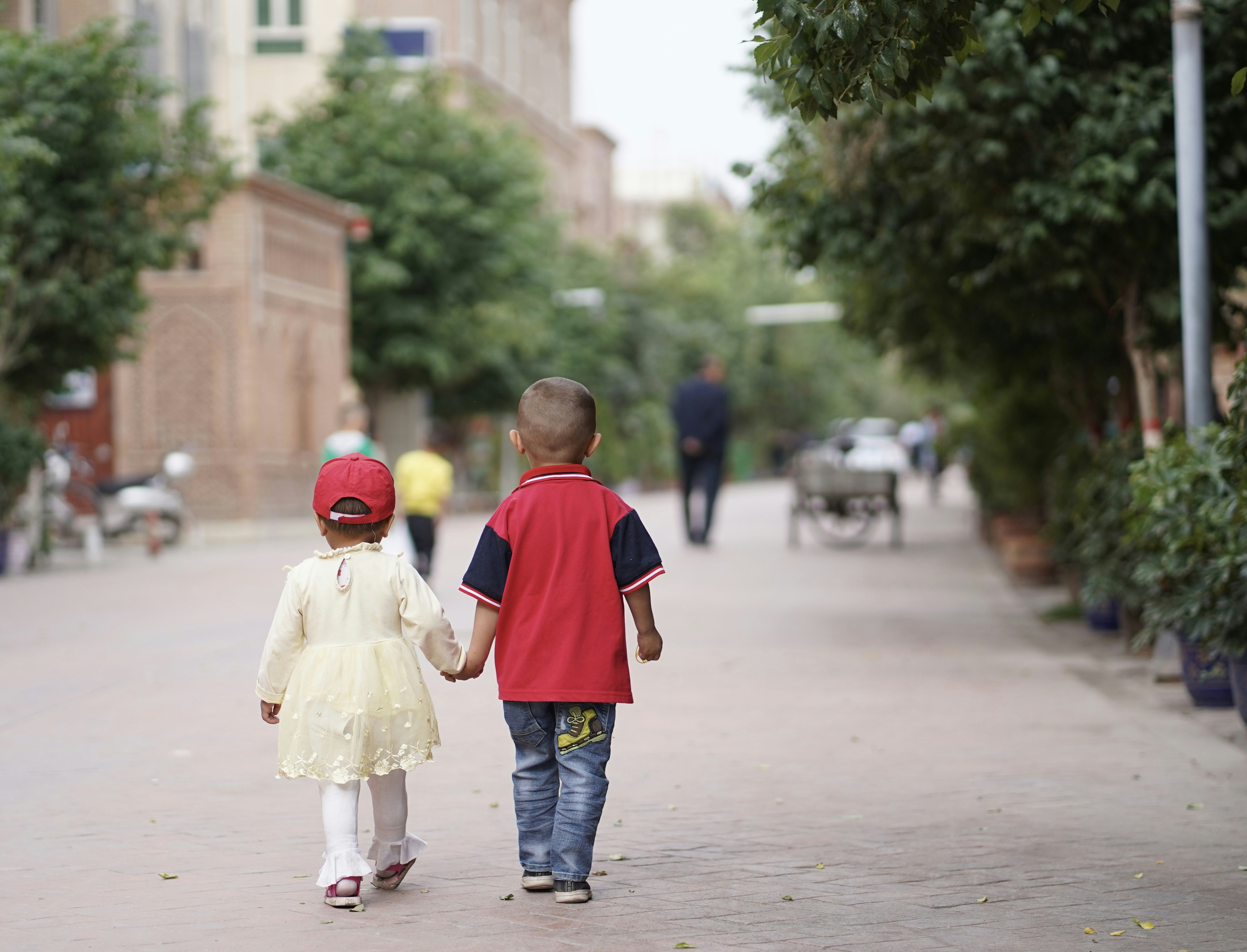 Junge in rotem und blauem Hemd und grauer Hose, der tagsüber Mädchen in weißem Kleid hält