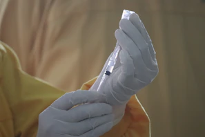 Close-up of hands wearing gloves packaging pharmaceutical products with care