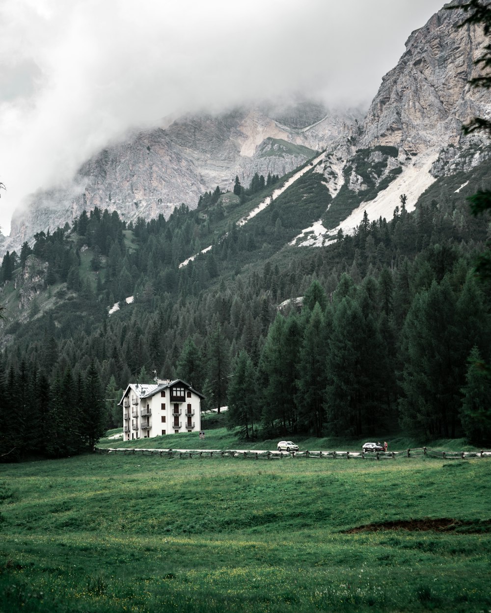 white concrete building on green grass field near green trees and mountain during daytime