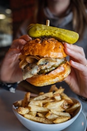 person holding burger with lettuce and cheese