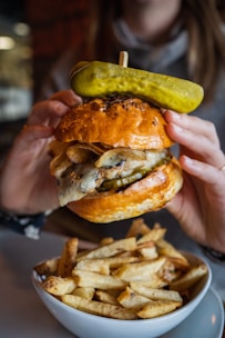 person holding burger with lettuce and cheese
