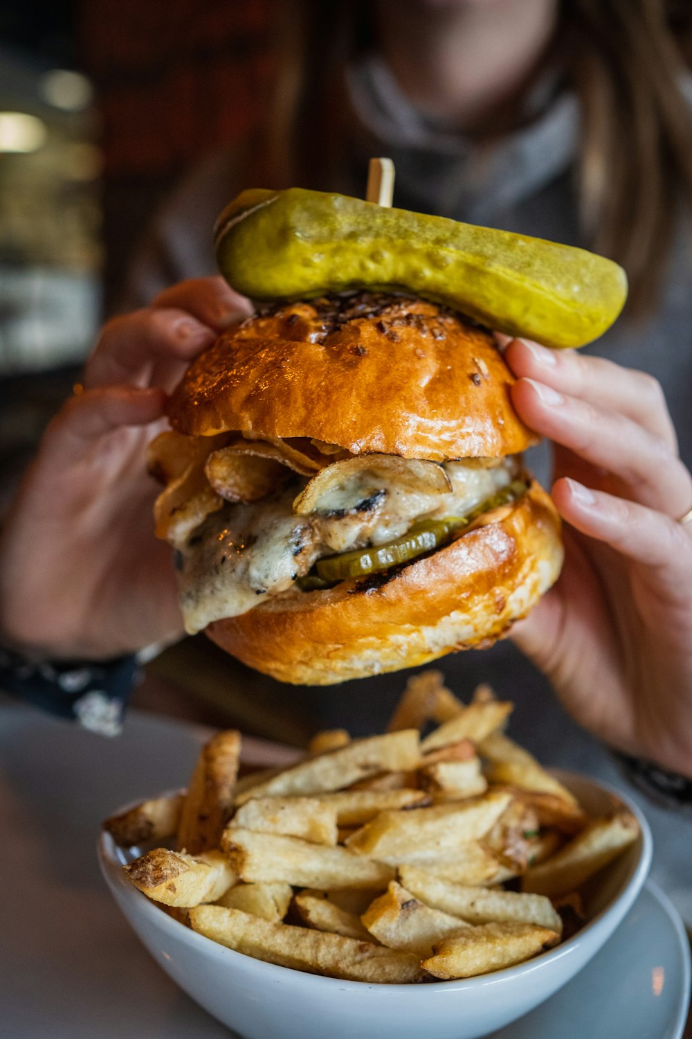 person holding burger with lettuce and cheese