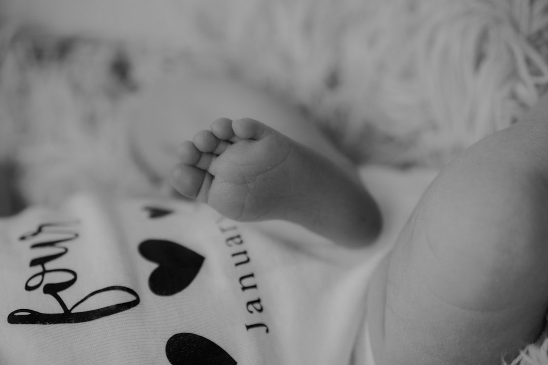 babys foot on white and black textile