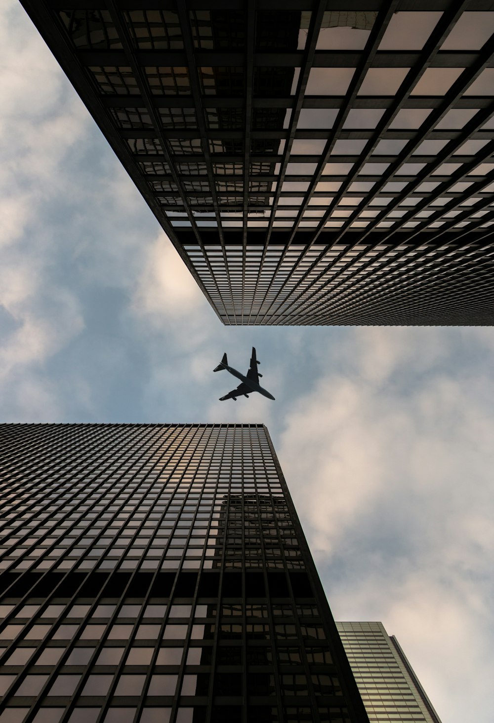 Tiefwinkelfotografie von Flugzeugen, die tagsüber über das Hochhaus fliegen