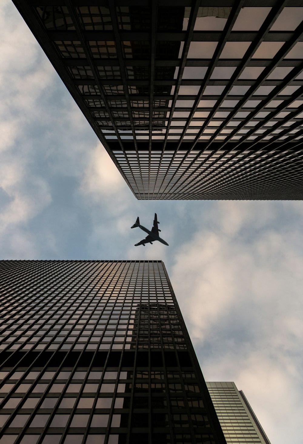 Fotografía de ángulo bajo de avión volando sobre el edificio de gran altura durante el día