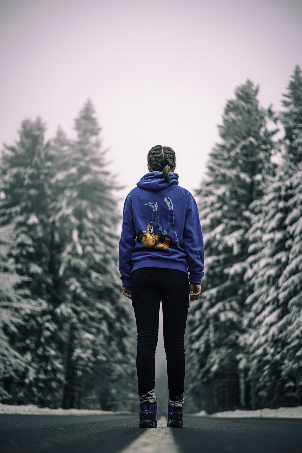 man in blue hoodie standing on snow covered ground