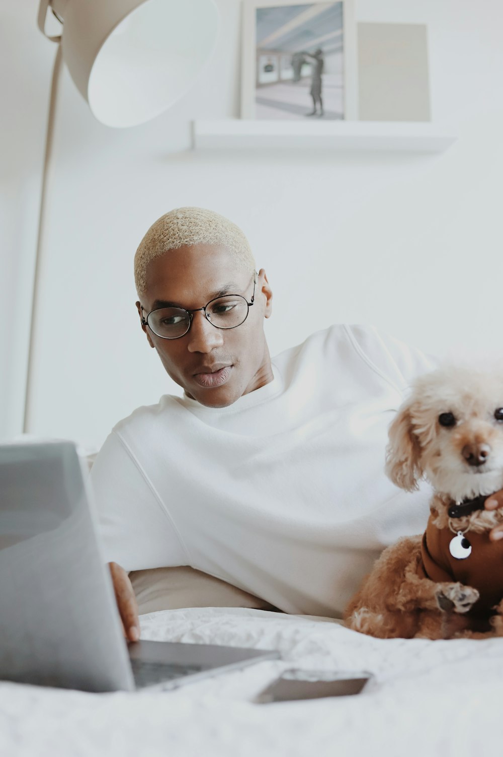 茶色の短いコートの小型犬を抱いている白いクルーネックシャツの男