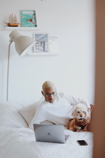 man in white shirt reading book on bed