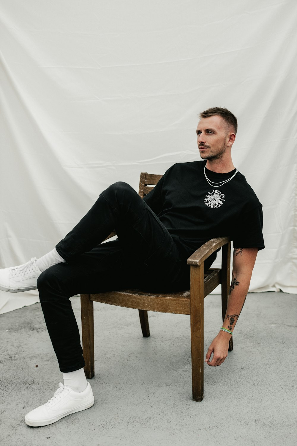 man in black crew neck long sleeve shirt sitting on brown wooden armchair