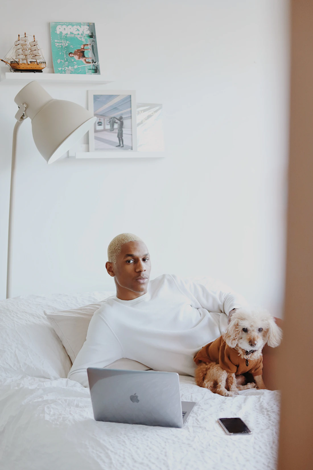 A young man relaxing on his bed beside his brown dog resting on the blanket