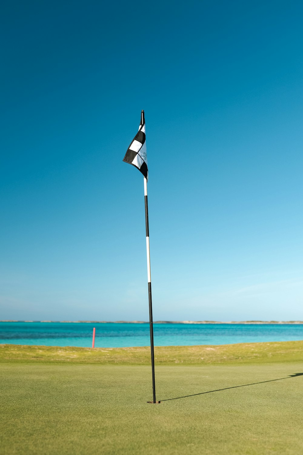 flag of us a on pole by the sea under blue sky during daytime
