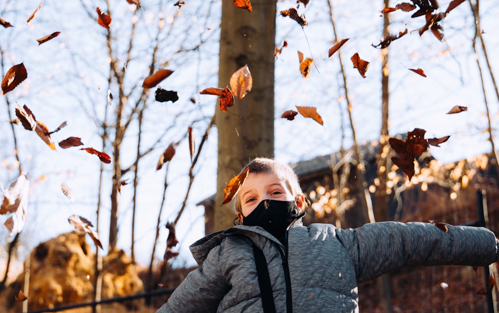 woman in gray jacket holding brown leaves during daytime