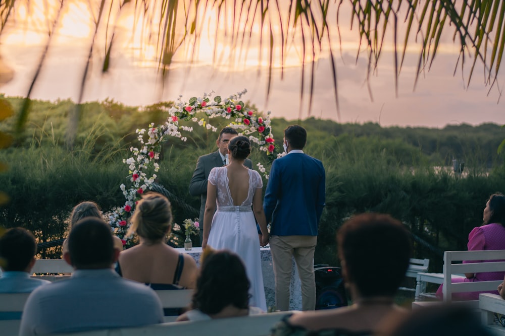 man in blue suit jacket standing beside woman in white sleeveless dress