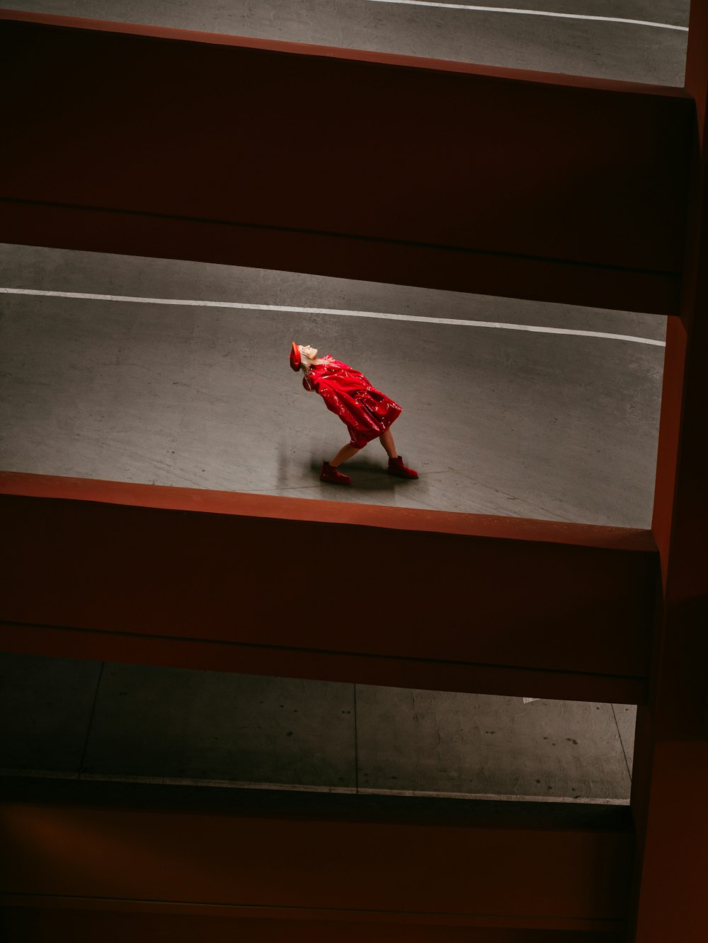 man in red and white long sleeve shirt and pants walking on gray concrete floor