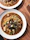Close-up of a steaming plate of traditional Spanish stew with fresh bread on the side.