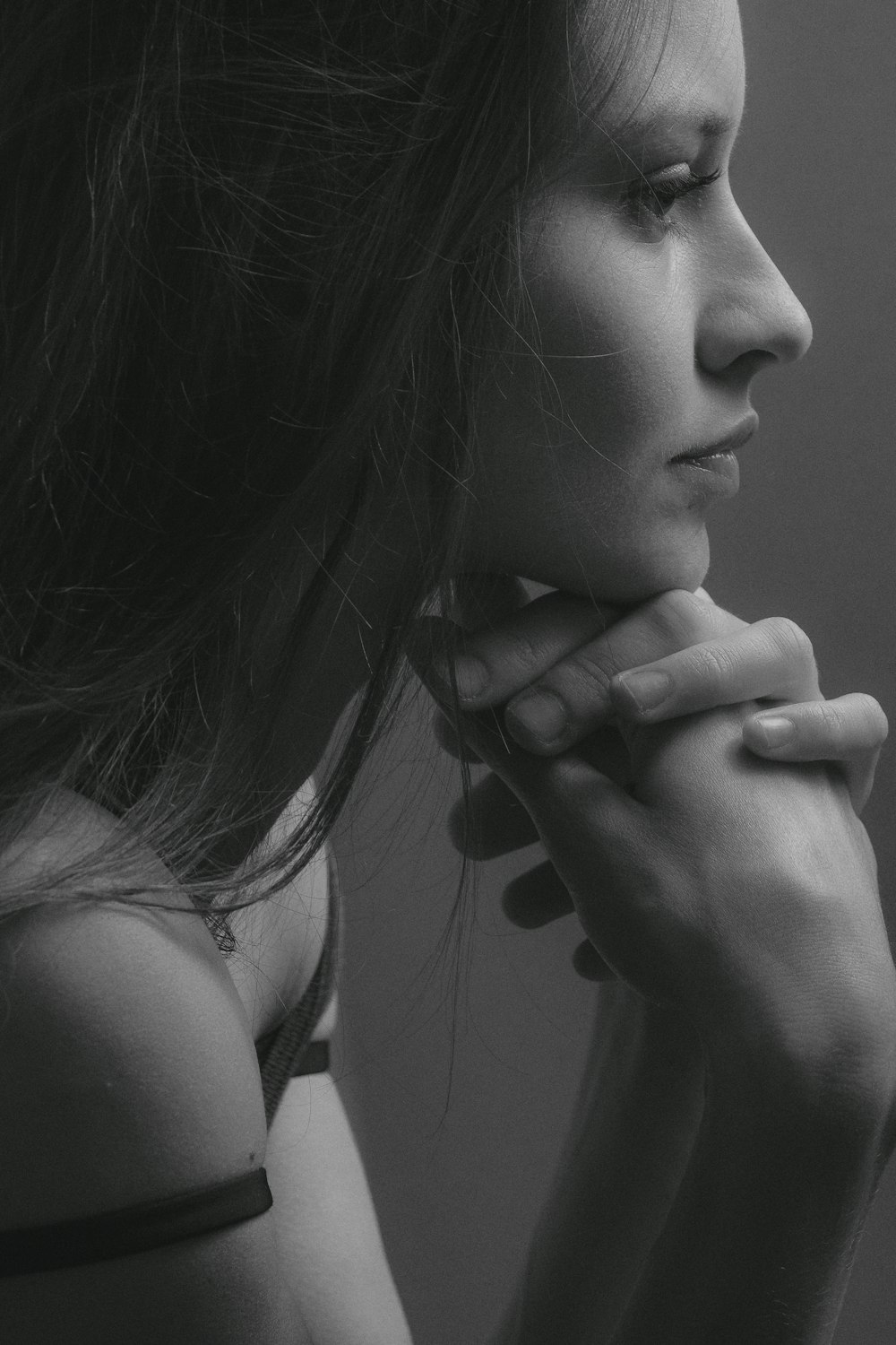grayscale photo of woman with hand on chin