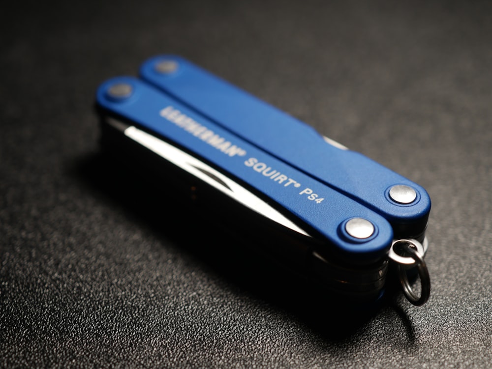 a blue keychain shaped like a lighter on a black surface