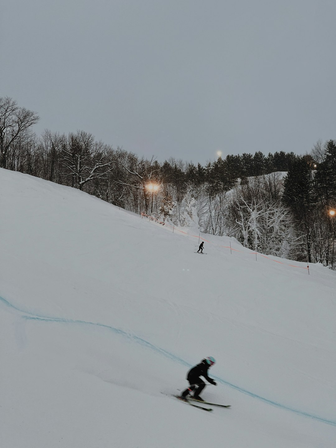 person in black jacket and black pants riding ski blades on snow covered ground during daytime
