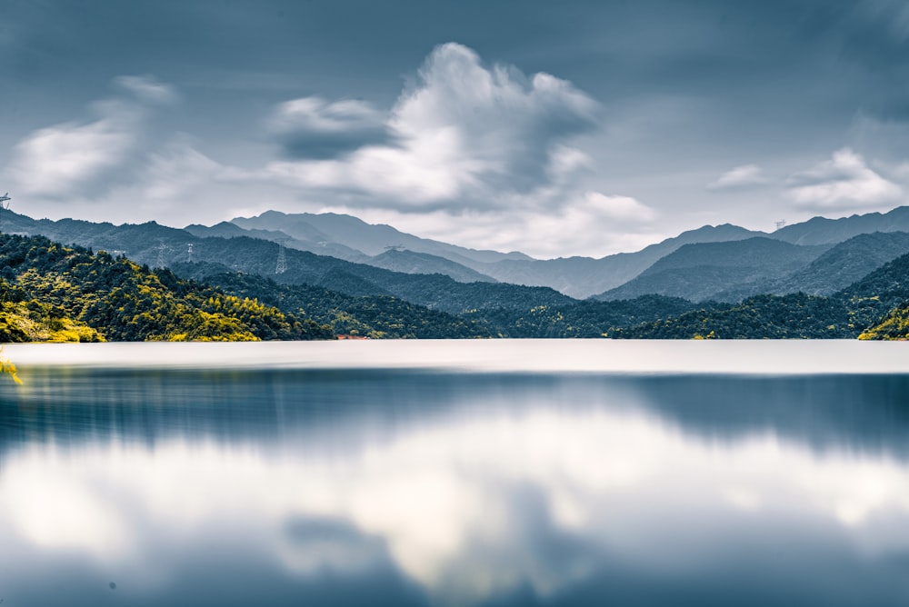 green trees near lake under cloudy sky during daytime