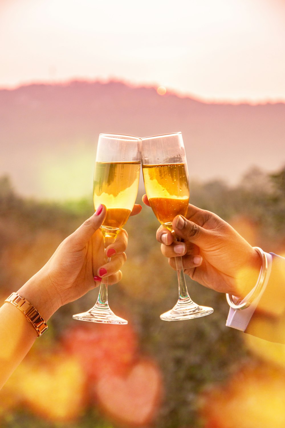 2 person holding clear drinking glasses with brown liquid